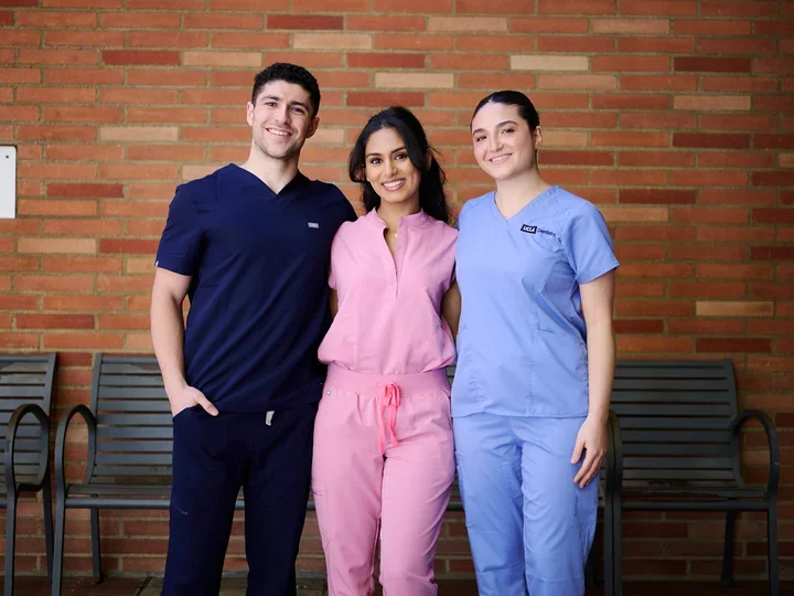 Three students taking a group picture in the breezeway.