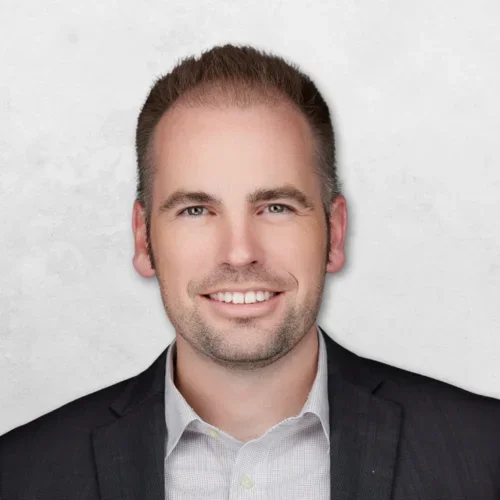 Andrei Marechek is wearing a black blazer over a white shirt and has short brown hair.