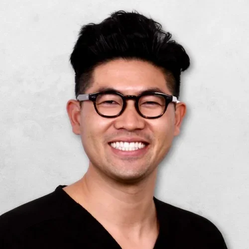 Anthony Nguyen is wearing glasses, has short black hair, and is wearing black scrubs