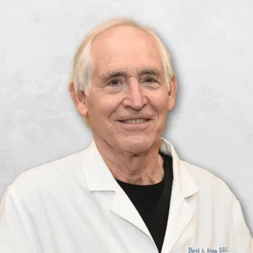Dr. Altman is wearing a white doctor's coat over a black shirt.