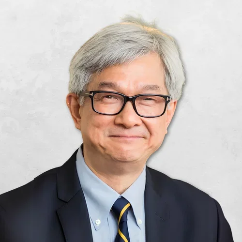 David WOng in a navy suit and striped tie, against a grey background