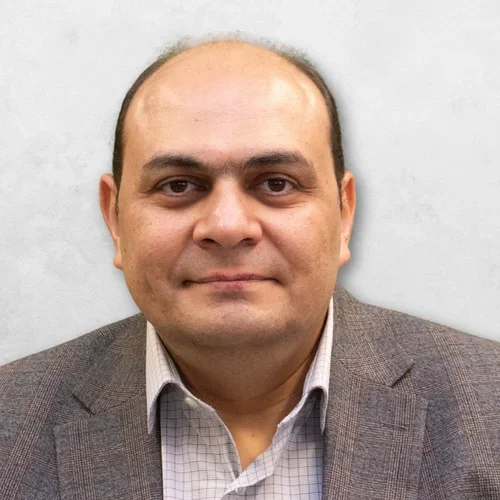 Dr. Ghoneima is wearing a tan sport coat over a light checkered collared shirt.