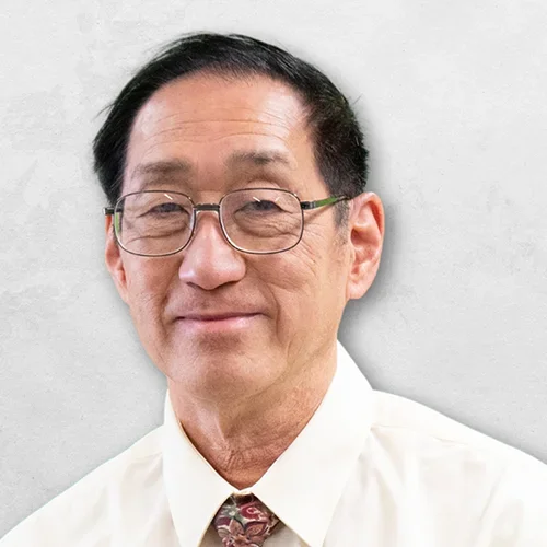 Dr. Kwong is wearing a light-colored collared shirt with a tie.