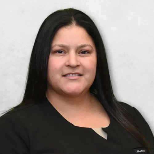 Guadalupe is wearing black scrubs and has long black hair