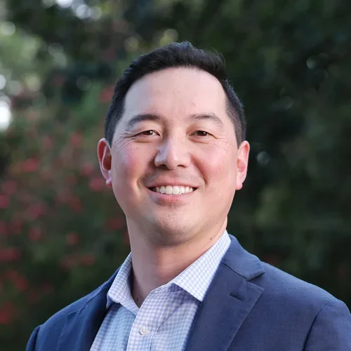 Dr. Hayashi is wearing a sport coat and a light blue button-up shirt.