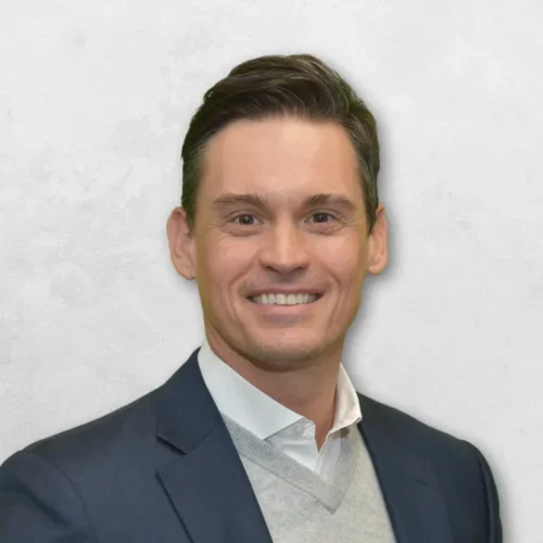 Jared Taylor Lee is wearing a suit over a grey sweater.