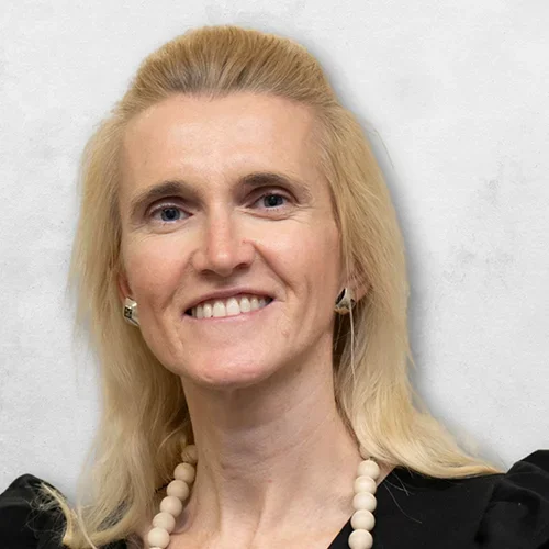 Dr. Kaczor-Uranowicz is wearing a black top and a necklace with large light brown beads.