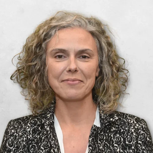 Marcia D. Botelho Dinis is wearing a black and white coat over a white shirt.