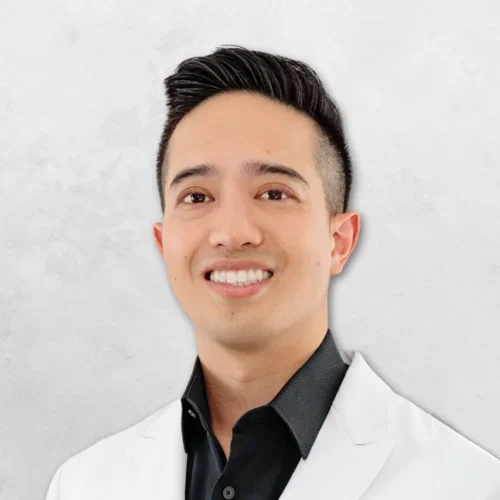 Michael Tuan Hoang is wearing a white doctor's coat over a black shirt.