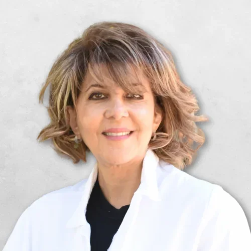 Dr. Mitra Elisha Simanian is wearing a white doctors coat over a black top