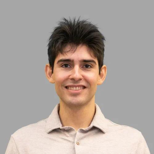 Lee Sanchez smiling in a tan dress shirt against a gray background