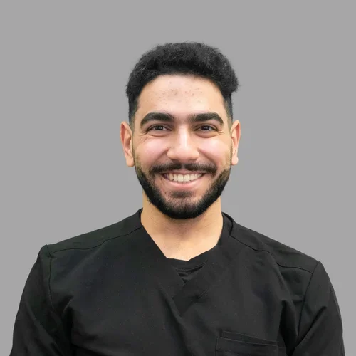 Mohammed Sedik smiling and wearing all black against a gray background