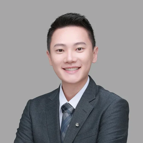 Huang Ting Lee in a dark-gray suit, against a light gray background