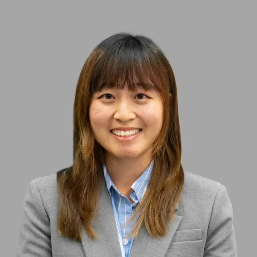 Dr. Sophie Kim is wearing a gray sport coat over a blue collared shirt.