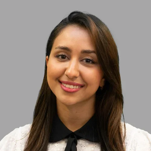 Dr. Kiana Saadatmand is wearing a white short-sleeve blouse with a black collar and tie.