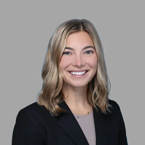 Dr. Caitlin Neapole is wearing a dark navy blazer over a soft taupe blouse.