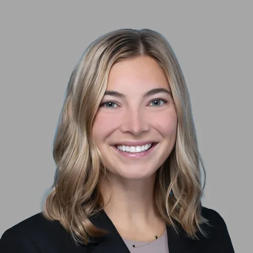 Dr. Caitlin Neapole is wearing a dark navy blazer over a soft taupe blouse.