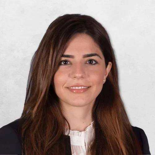 Soma Esmailian Lari has long brown hair and is wearing a black blazer over a white top.