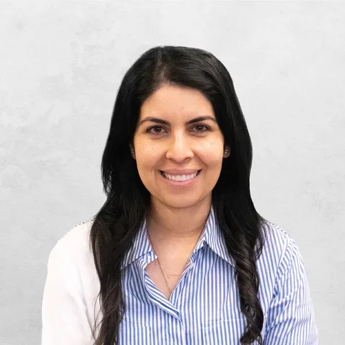 Dr. Orly Hendizadeh is wearing a striped blouse and a sweater on the left shoulder.