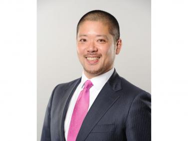                           Dr. Yusuke Hamada smiling, wearing a black suit with pink tie