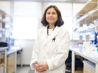 Dr. Yvonne Hernandez-Kapila, wearing a white lab coat in a lab.