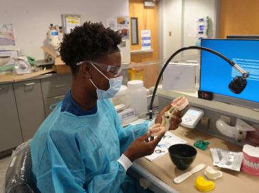 student examines a typodont in a denal laboratory