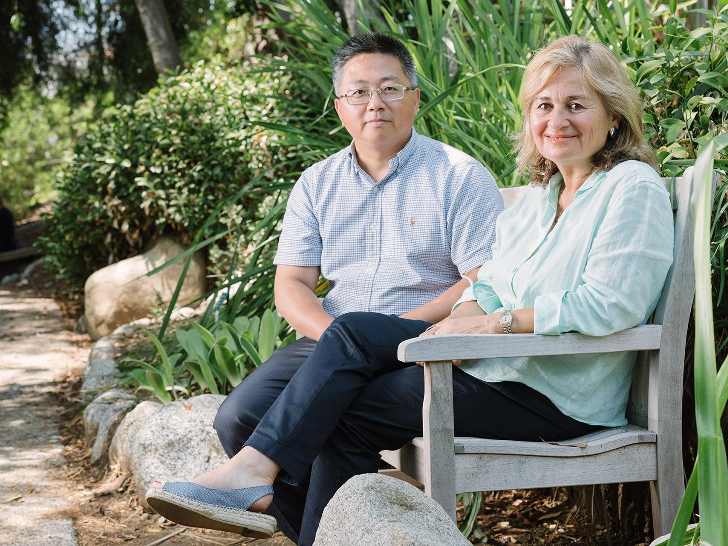 Drs. Shen Hu and Diana Messadi sitting on a bench in the  UCLA Mildred E. Mathias Botanical Garden