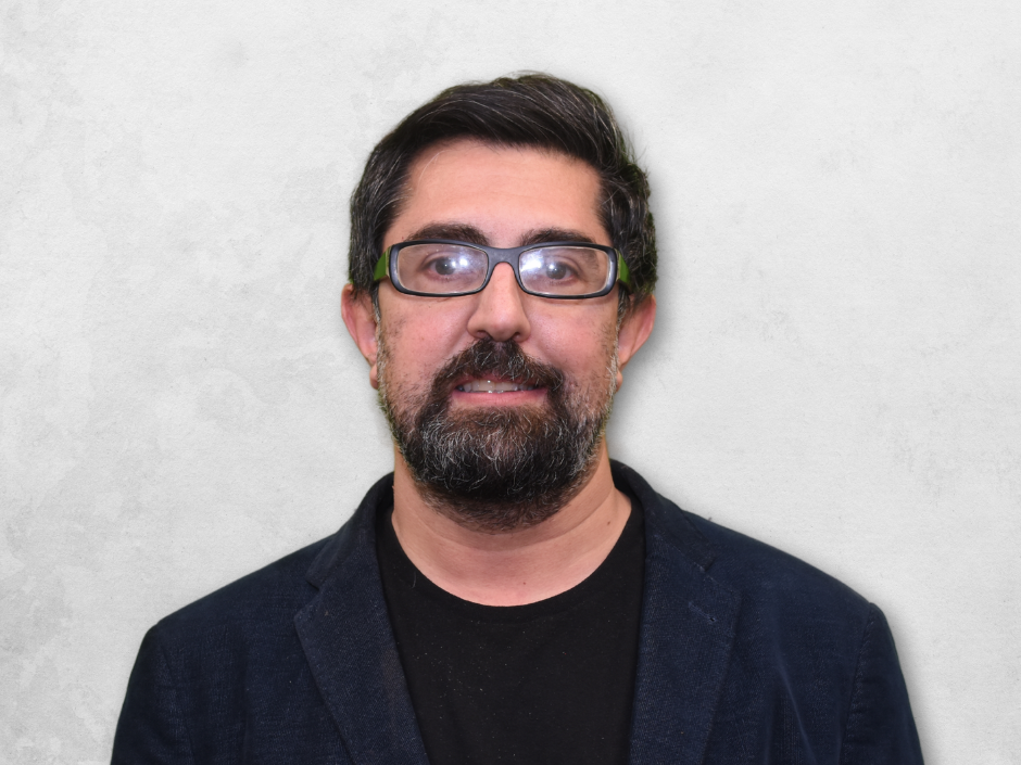 Seyed Hossein Beheshti is wearing a blue blazer over a black shrit and has glasses.