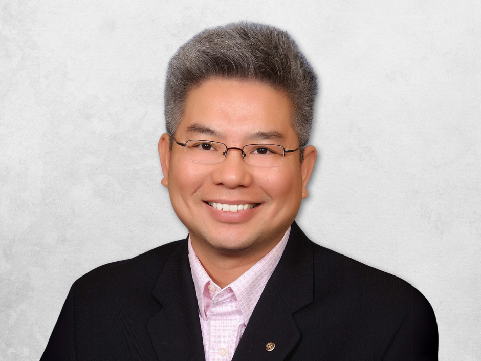 William D. Nguyen is wearing a black suit with a pink shirt. He is also wearing glasses.
