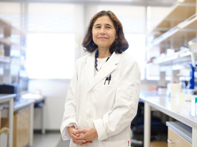 Dr. Yvonne Hernandez-Kapila, wearing a white lab coat in a lab.