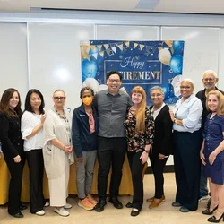 Ten people smiling in front of "Happy Retirement" banner