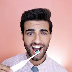 Kishen Godhia demonstrating proper toothbrushing technique with an electric toothbrush.
