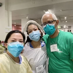 Two UCLA Dentistry students pose in masks with Dr. Edmond Hewlett, at right