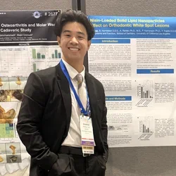 Andrew Tran posing with research poster