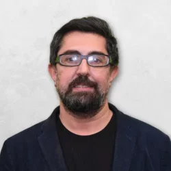 Seyed Hossein Beheshti is wearing a blue blazer over a black shrit and has glasses.