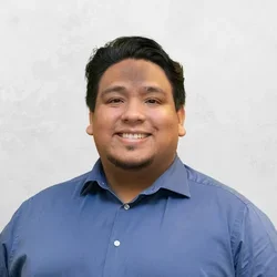 Daniel Castillo is wearing a medium blue button-up shirt.