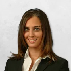 Dr. Termeie has long brown hair and is wearing a black blazer with a white shirt.