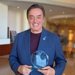 man in blue suit holding crystal award