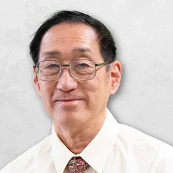 Dr. Kwong is wearing a light-colored collared shirt with a tie.