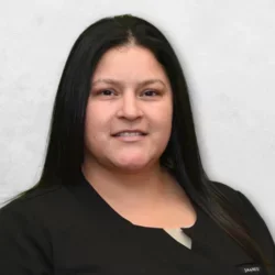 Guadalupe is wearing black scrubs and has long black hair