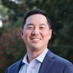 Dr. Hayashi is wearing a sport coat and a light blue button-up shirt.