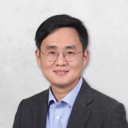 Jaemin Ko is wearing a gray suit jacket over a blue shirt.