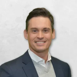 Jared Taylor Lee is wearing a suit over a grey sweater.