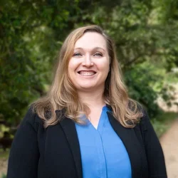 Dr. Owens is dressed in a black blazer layered over a blue blouse