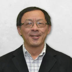 Dr. Shen is wearing a black blazer over a checkered white shirt.