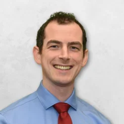 Dr. Mullen is wearing a blue collared shirt with a red tie