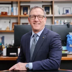 Paul Krebsbach in navy suit, seated at a desk