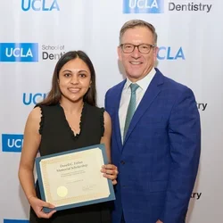 Paul Krebsbach, at left, presents an award to a dental student.
