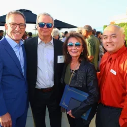 Group of four people. Woman third from left is holding a blue award folder