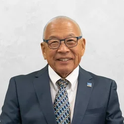 Dr. Ronaldo Mito is wearing a suit and tie over a white collared shirt.